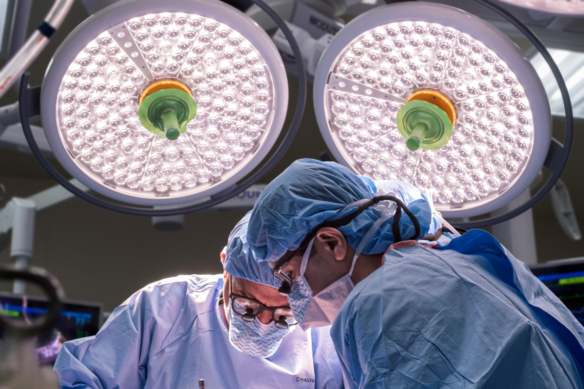 Two surgeons operating under large lights